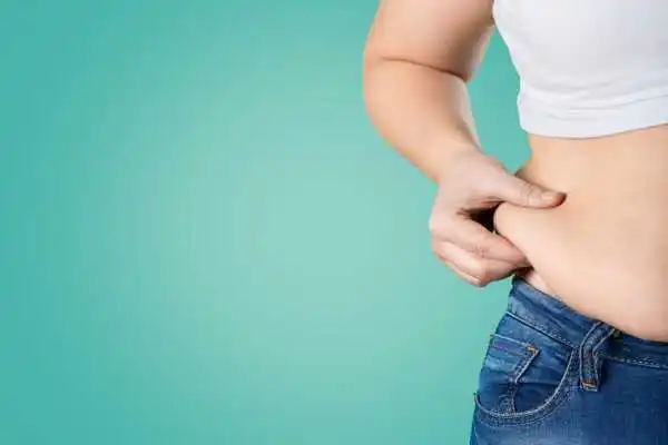 Image of woman pinching her love handles to show weight gain Hertford